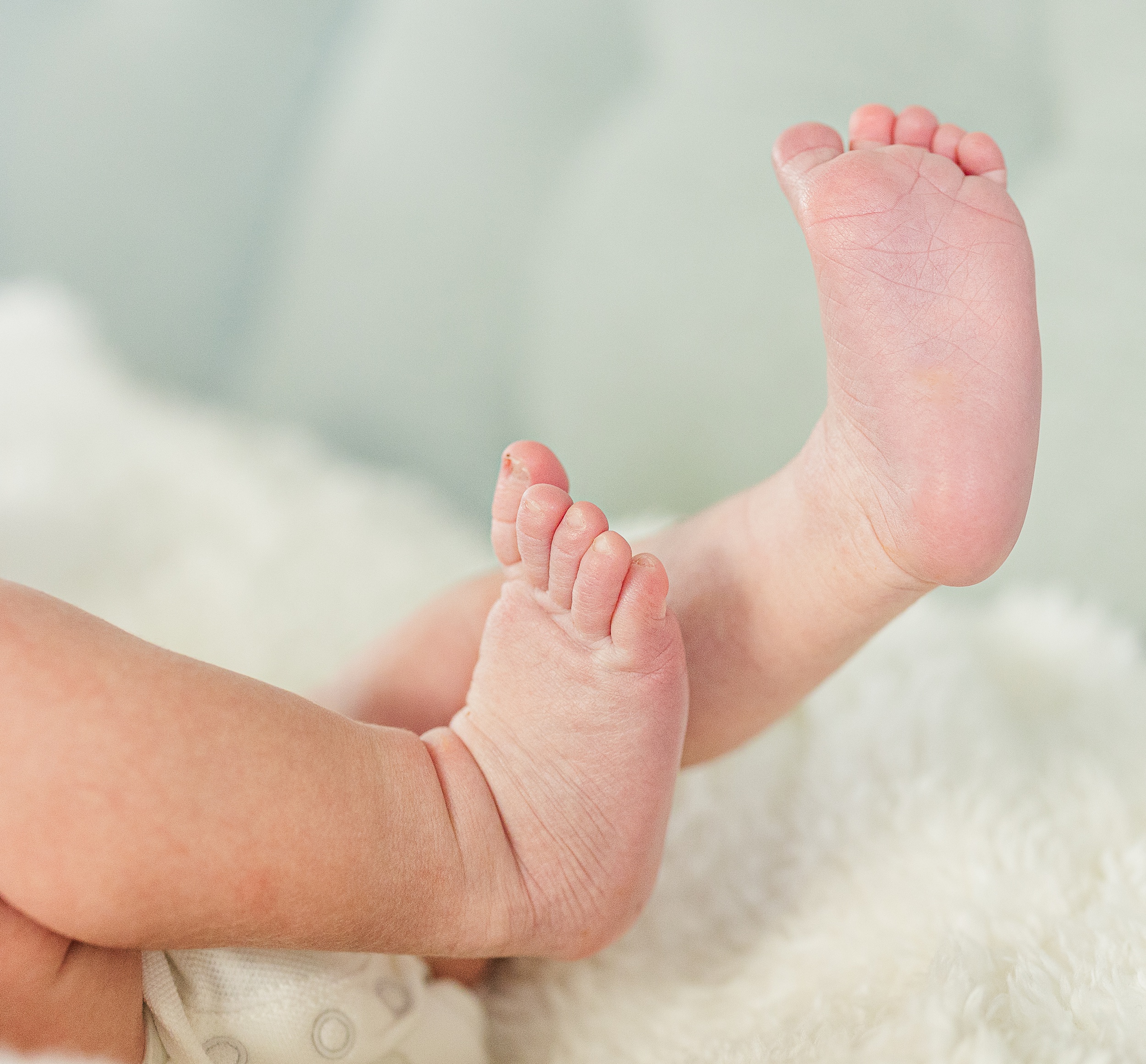 Details of a baby's feet while laying on a white blanket