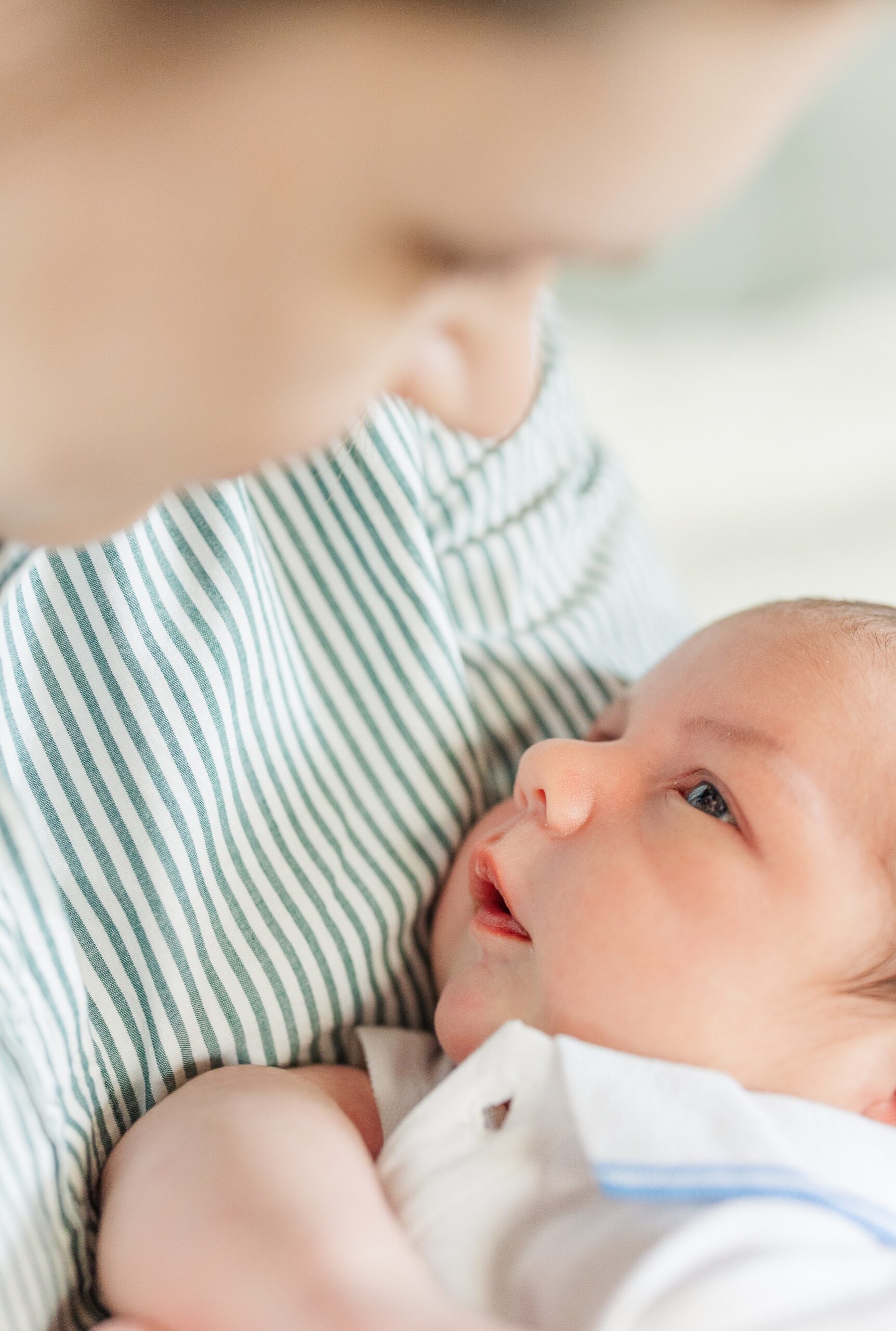 A baby lays in mom's arms looking back up at her after meeting a postpartum doula in Ann Arbor