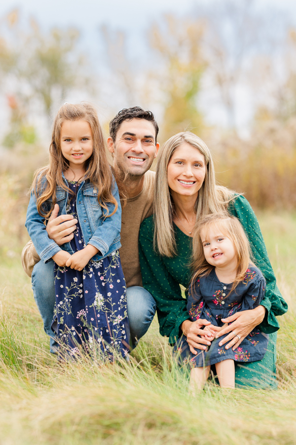 Happy mom and dad hug and smile with their two toddler daughters during things to do in ann arbor with toddlers