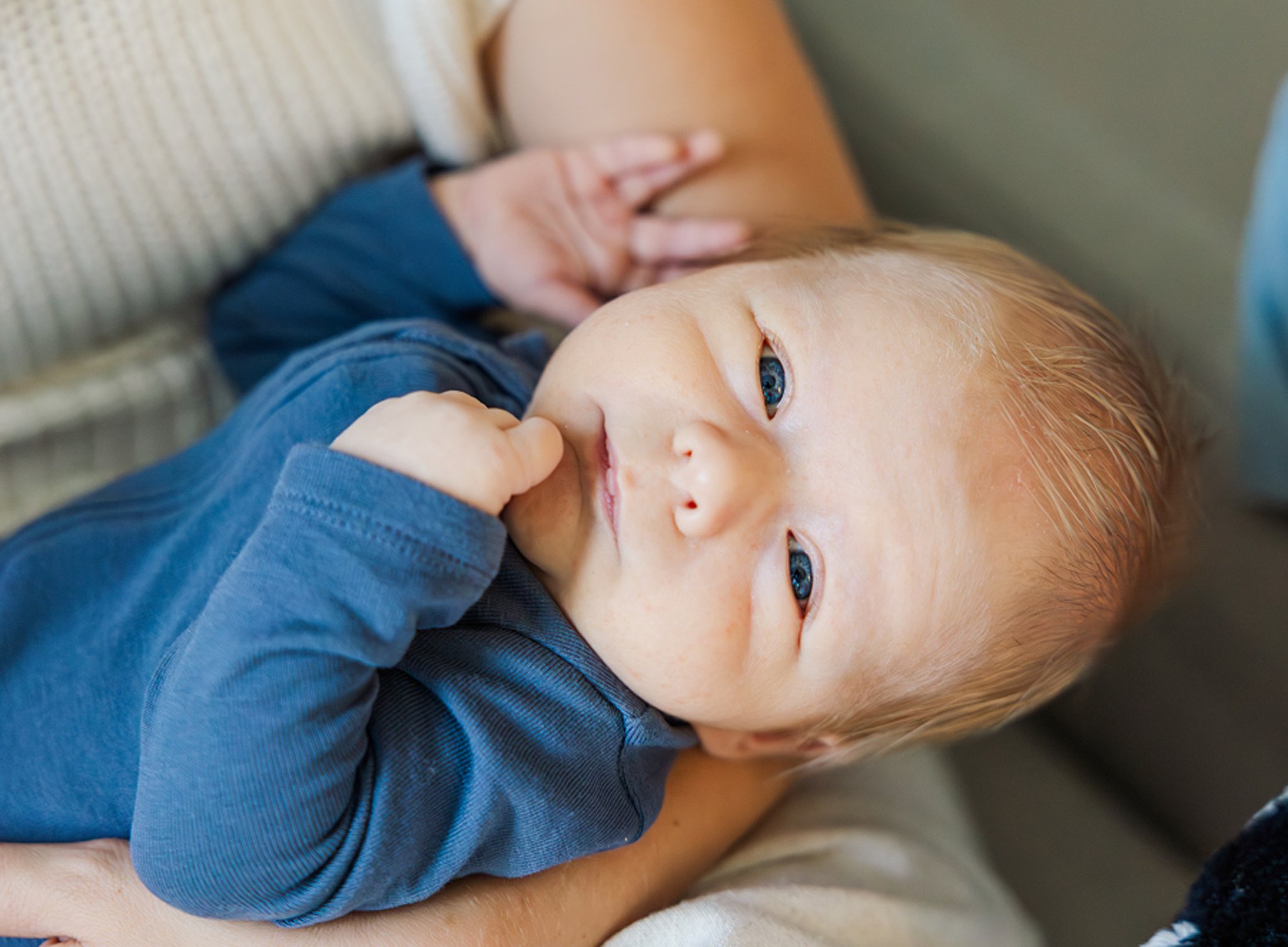 A newborn baby lays in mom's arms with eyes open